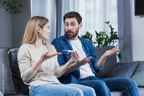 Sad man and woman sitting on the couch, disappointed with a negative pregnancy test photo