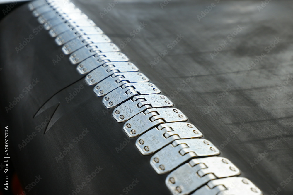 Close-up of a rubber conveyor belt connected by a flexible metal joint.Selective focus.