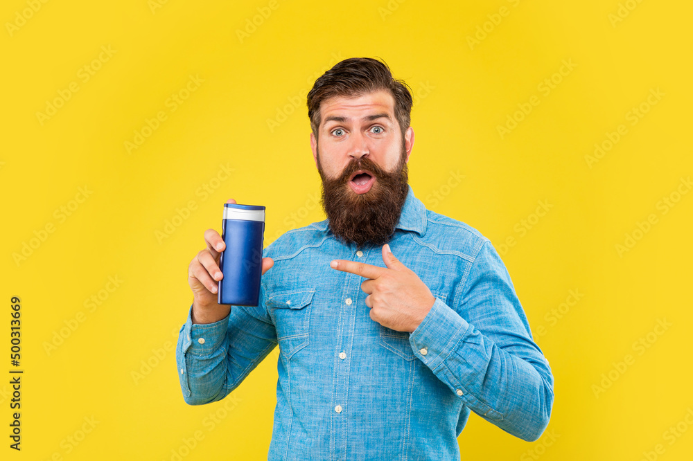 surprised brutal bearded man point finger on hair conditioner bottle on yellow background, skincare surprised brutal bearded man point finger on hair conditioner bottle on yellow background, skincare