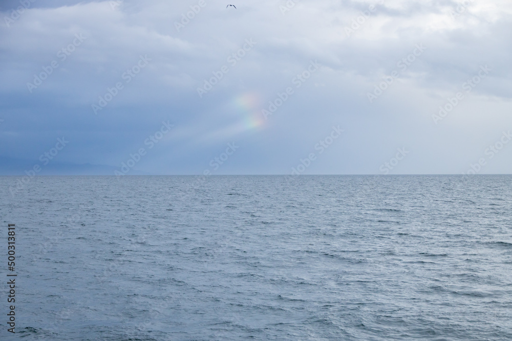 Double rainbow spots in the sky over the ocean Double rainbow spots in the sky over the ocean