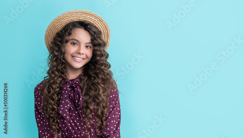 girl smile in straw hat with long brunette curly hair on blue background