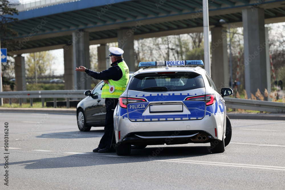  Policjant policji drogowej podczas kierowania ruchem z lizakiem do zatrzymywania pojazdów. - obrazy, fototapety, plakaty 