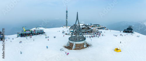 Historic peace bell concordia on peak of kronplatz. Aerial view of beautiful tourist attraction on snowy landscape. Italian monument in alps. photo