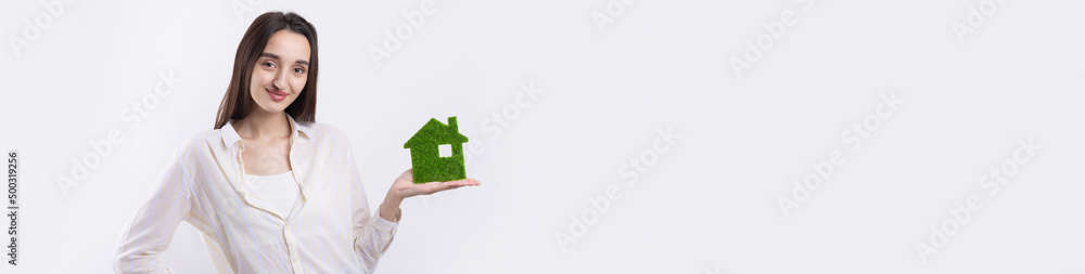 A young girl realtor holds a model of a green house in her hands. Sale of ecological real estate. A young girl realtor holds a model of a green house in her hands. Sale of ecological real estate.