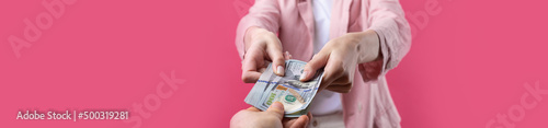 A woman in a pink jacket receives a bribe in dollars against a red background.