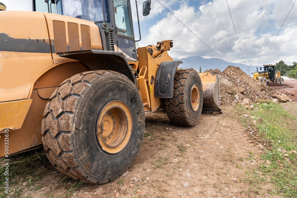 Obraz premium Rubber wheel loader yellow excavator. Heavy-duty machine for earth and road repairs. 