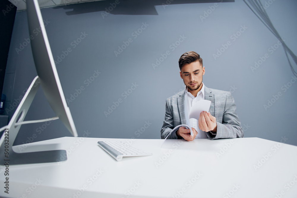 handsome man working at the computer in the office scatters documents Gray background handsome man working at the computer in the office scatters documents Gray background