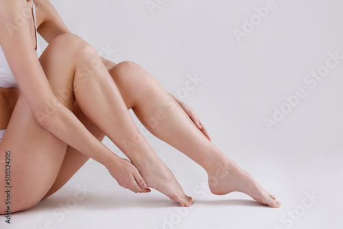 Cropped shot of woman's legs after body hair removal procedures. Unrecognizable woman showing her calves over isolated white background. Copy space for text, close up. © Evrymmnt