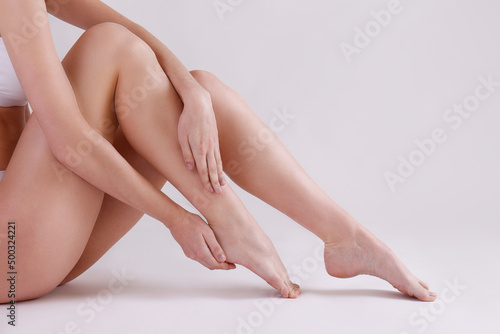 Cropped shot of woman's legs after body hair removal procedures. Unrecognizable woman showing her calves over isolated white background. Copy space for text, close up. © Evrymmnt