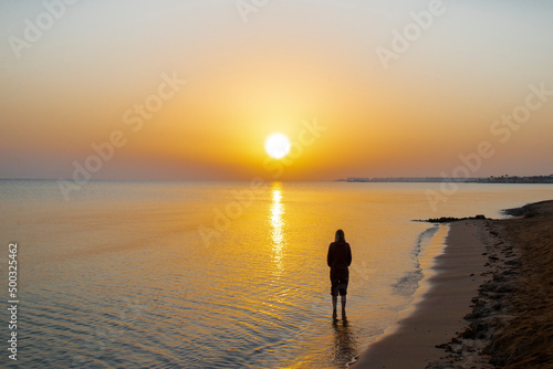 Silhouette of woman looking at a landscape of sunrise  sun  sky and beach on the shores of the Red Sea in Hurgada  Egypt