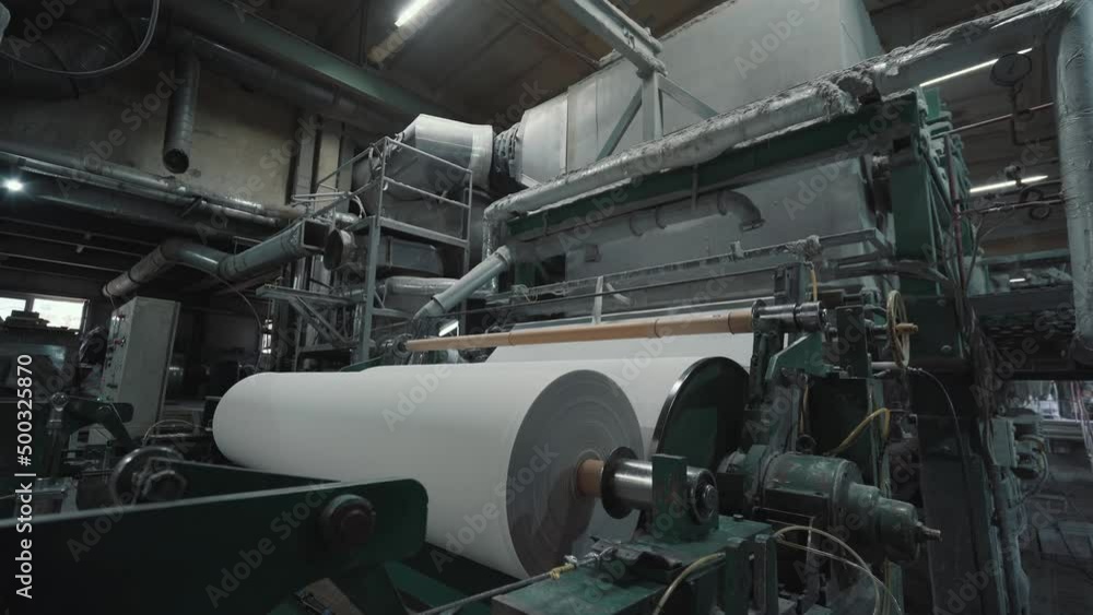 Production machine with rolls of new paper in waste paper recycling factory.