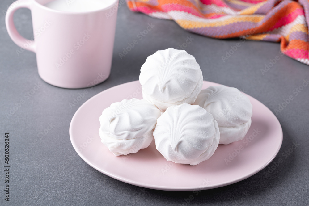 White marshmallows on a pink plate on a grey table White marshmallows on a pink plate on a grey table