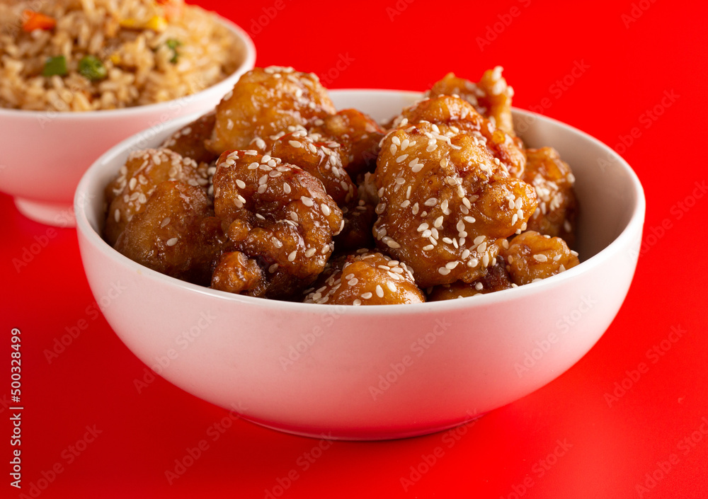 Bowl of Sesame Chicken on a Bright Red Background Bowl of Sesame Chicken on a Bright Red Background