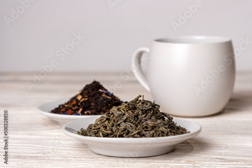 varieties of black and green tea in saucers on a white background