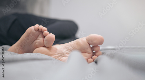 Close-up of male legs with feet forward lying on the bed while resting. Vacation concept