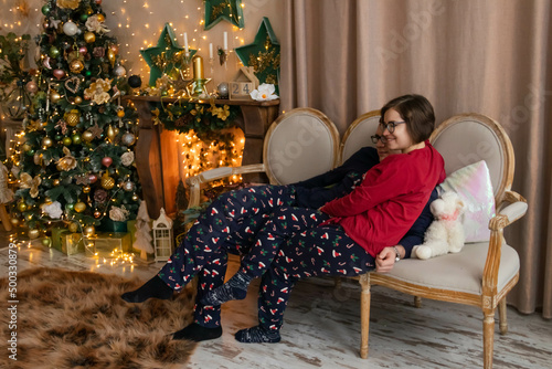 Canvas Print husband and wife are sitting on the couch in pajamas near the Christmas tree and