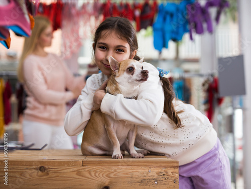 Portrait of happy kid girl with her dog standing in pet shop during shopping with mother © JackF