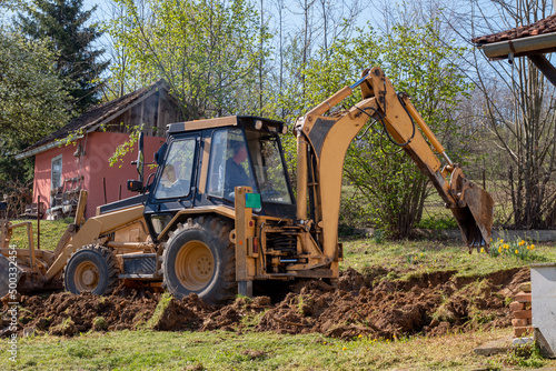 Bucket excavator at work in the countryside in a private yard. .Digging the ground, clearing land and landscaping works with specialized machinery. photo