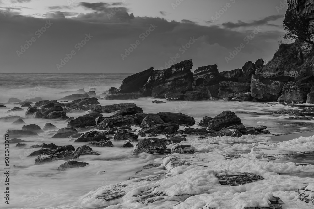 Seascape with sea foam and rocks in black and white