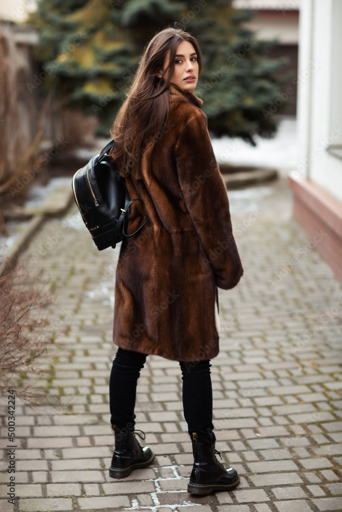 Glamorous funny young woman with smile wearing brown fashionable fur coat. Fur and fashion concept. Beautiful people.