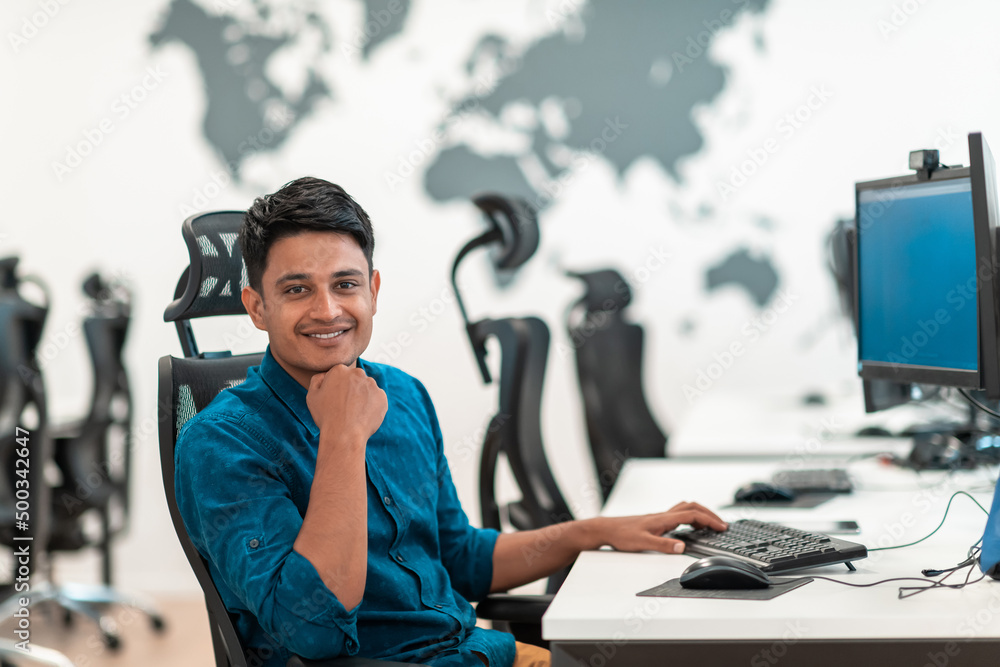 Casual business man working on desktop computer in modern open plan startup office interior. Selective focus Casual business man working on desktop computer in modern open plan startup office interior. Selective focus