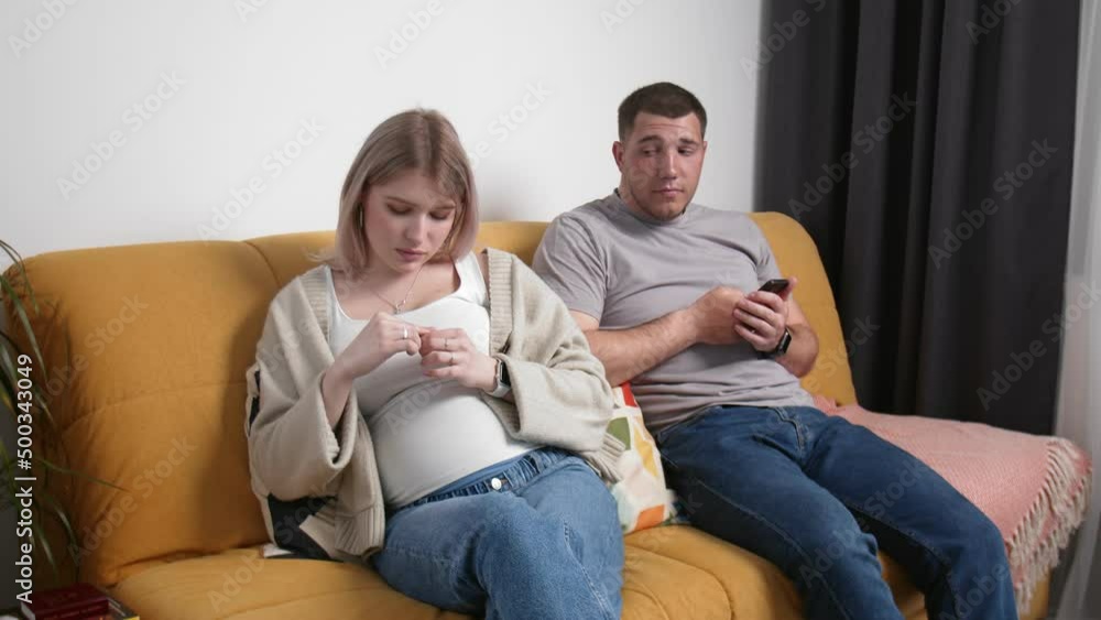 A couple expecting a baby offended each other on the couch. A man embraces his woman. Young family A couple expecting a baby offended each other on the couch. A man embraces his woman. Young family