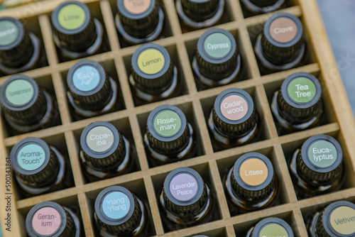 Top-down view of essential oil bottles in wooden storage box with colorful cap stickers photo