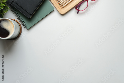 Top view white office desk with notebook, coffee cup and eyeglasses. Copy space for text.