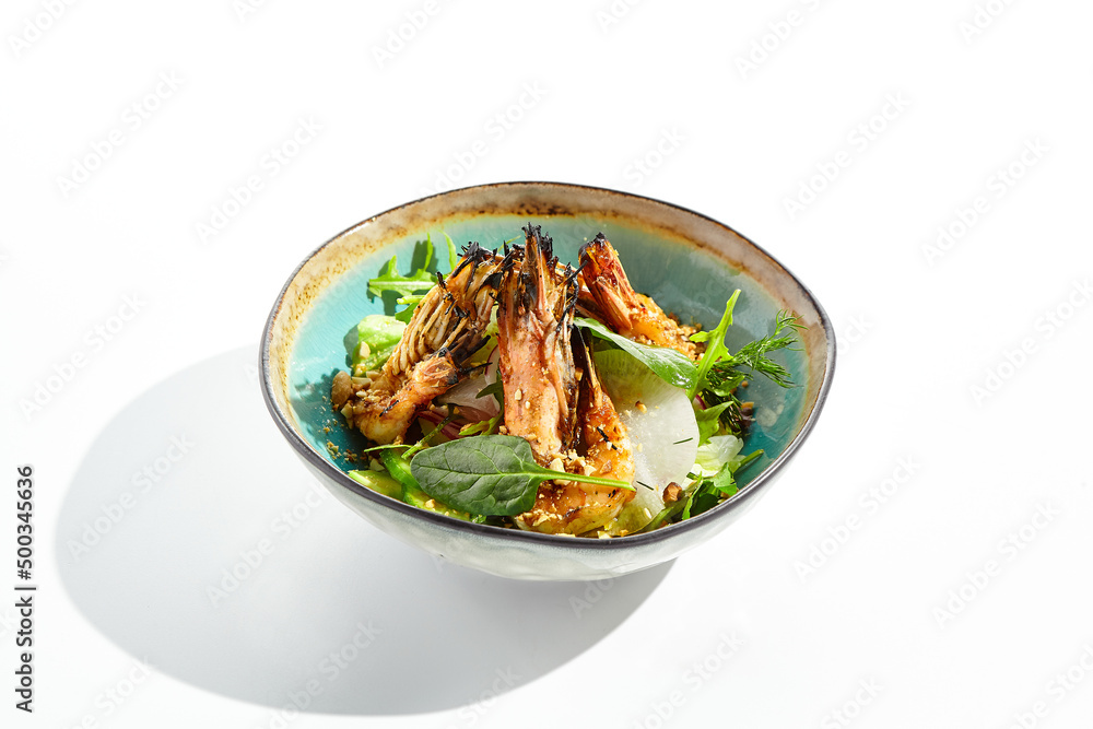 Green salad with grilled prawns and vegetables. Healthy food in restaurant menu. Shrimp with salad mix and peanuts - delicious dish for keto diet. Restaurant dish isolated on white background. Green salad with grilled prawns and vegetables. Healthy food in restaurant menu. Shrimp with salad mix and peanuts - delicious dish for keto diet. Restaurant dish isolated on white background.