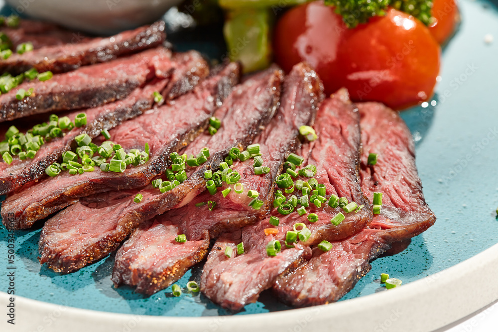 Roast beef with vegetables and sauce on trendy plate. Sliced meat steak roast grill with tomatoes and broccoli isolated on white table. Angus roast beef in healthy style for restaurant. Roast beef with vegetables and sauce on trendy plate. Sliced meat steak roast grill with tomatoes and broccoli isolated on white table. Angus roast beef in healthy style for restaurant.