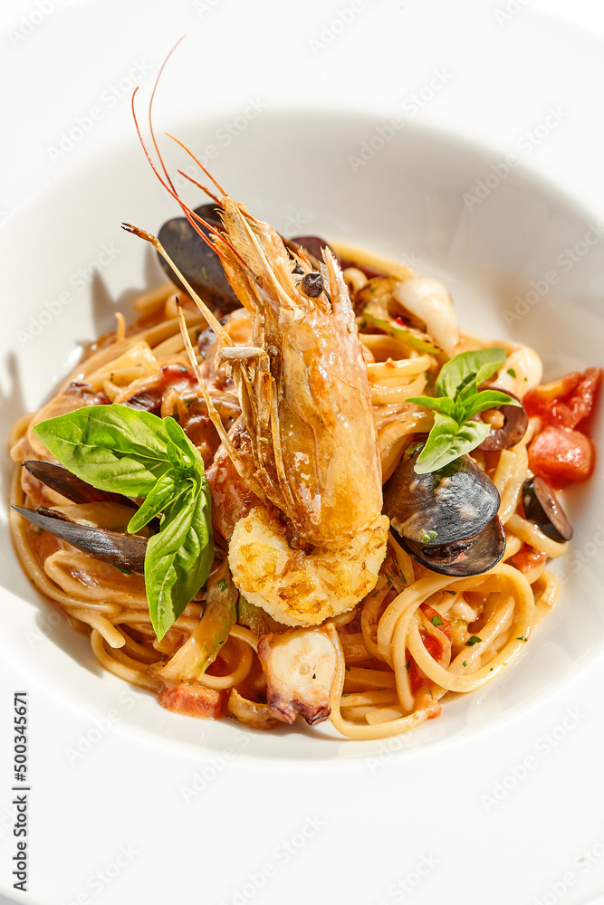 Italian dish - seafood linguine isolated on white background. Pasta with prawn, mussels, octopus,  squid in tomatoes marinara sauce. Seafood pasta in Italian restaurant menu. Seafood on white plate