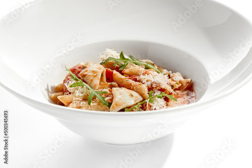 Traditional Italian dish - penne with salmon and squid with tomato sauce and olives. Penne marinara with seafood on white table. Italian seafood pasta in arrabiata sauce - healthy mediterrian lunch.