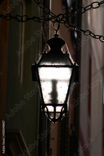 Vintage Outdoor Frosty Lamp with Cobwebs and Chains in Dark Allyway Isolated photo