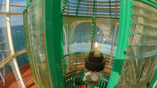 Static inside shot of the lantern room of a lighthouse during a bright sunny day with the fresnel lens moving by the lamp light photo