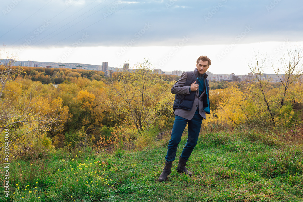 Tall handsome man outdoor in autumn forest on the hill