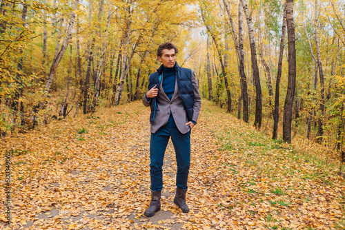 Tall handsome man walking in the autumn alley