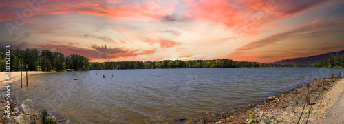 a stunning panoramic shot of the vast rippling green waters of a lake surrounded by lush green trees with powerful clouds at sunset at Dallas Landing Park in Acworth Georgia USA photo