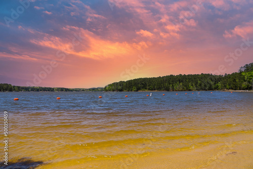 a gorgeous rippling lake surrounded by lush green pine trees, grass and plants with powerful clouds at sunset at Dallas Landing Park in Acworth Georgia USA photo