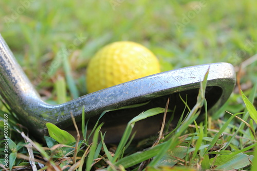 Close up of a yellow golf ball and an iron club head photo