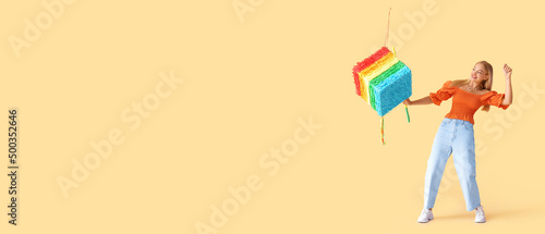 Young woman breaking Mexican pinata on beige background with space for text