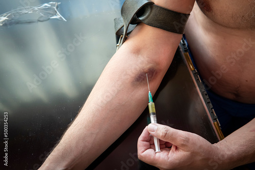 Foto Addict injecting heroin dose to his hand with syringe