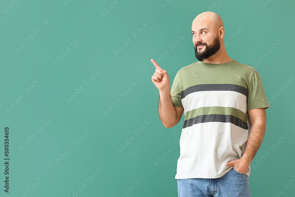 Portrait of handsome bald man pointing at something on green background Portrait of handsome bald man pointing at something on green background