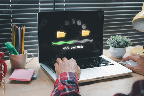 Transfer files data system relocation concept, Person hand using laptop computer waiting for transfer file process with loading bar icon on virtual screen. photo