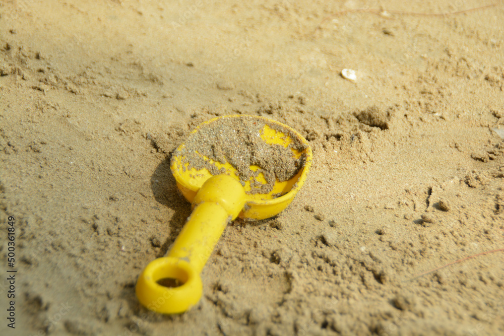 Yellow spade kids toy was placed on sand at the beach. Yellow spade kids toy was placed on sand at the beach.