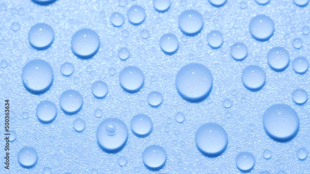 Close-up transparent water drops texture rotating on blue chroma key background Close-up transparent water drops texture rotating on blue chroma key background