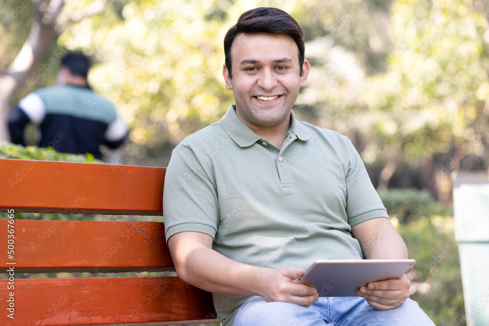 Man using digital tablet at park Man using digital tablet at park