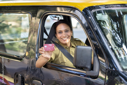 Woman taxi driver showing card sitting inside car © G-images