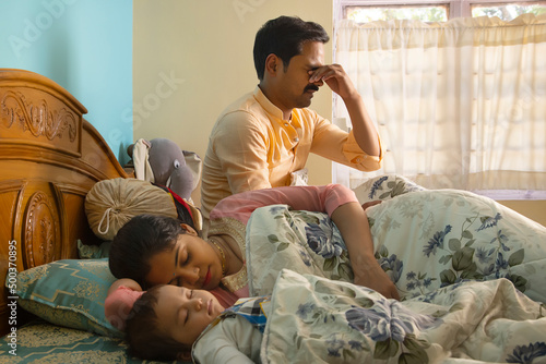 Father waking up in the morning while mother and baby sleeping on bed