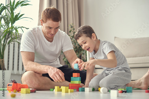 smiling father and little son playing with colorful blocks together at home. Playtime. diverse family