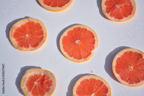 Colorful fruit pattern of fresh grapefruit slices on white background. Minimal flat lay concept.